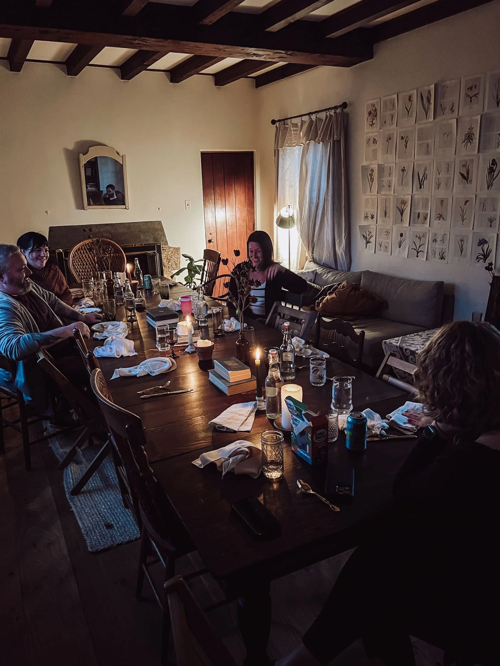 A group of people laughing and talking at a long candlelit table