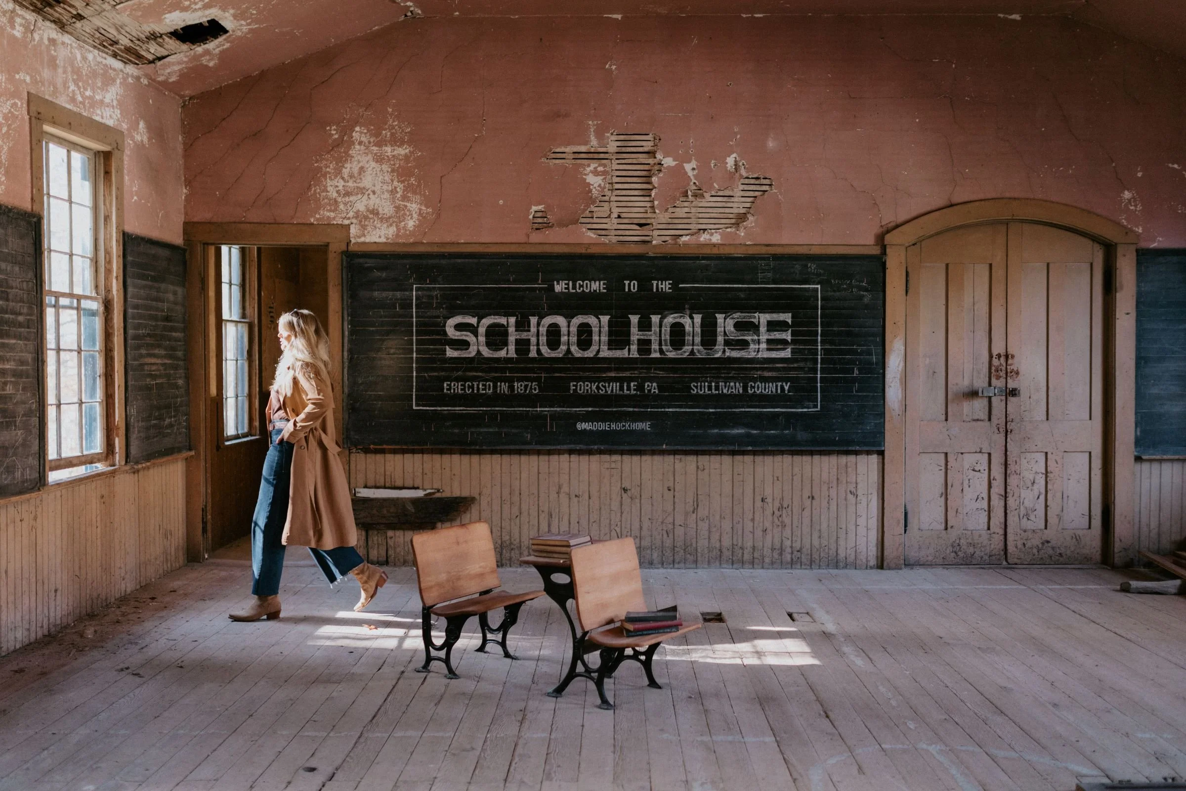 A tall, blonde woman walking in a one room schoolhouse being renovated by Maddie Hock Home in Forksville, Pennsylvania