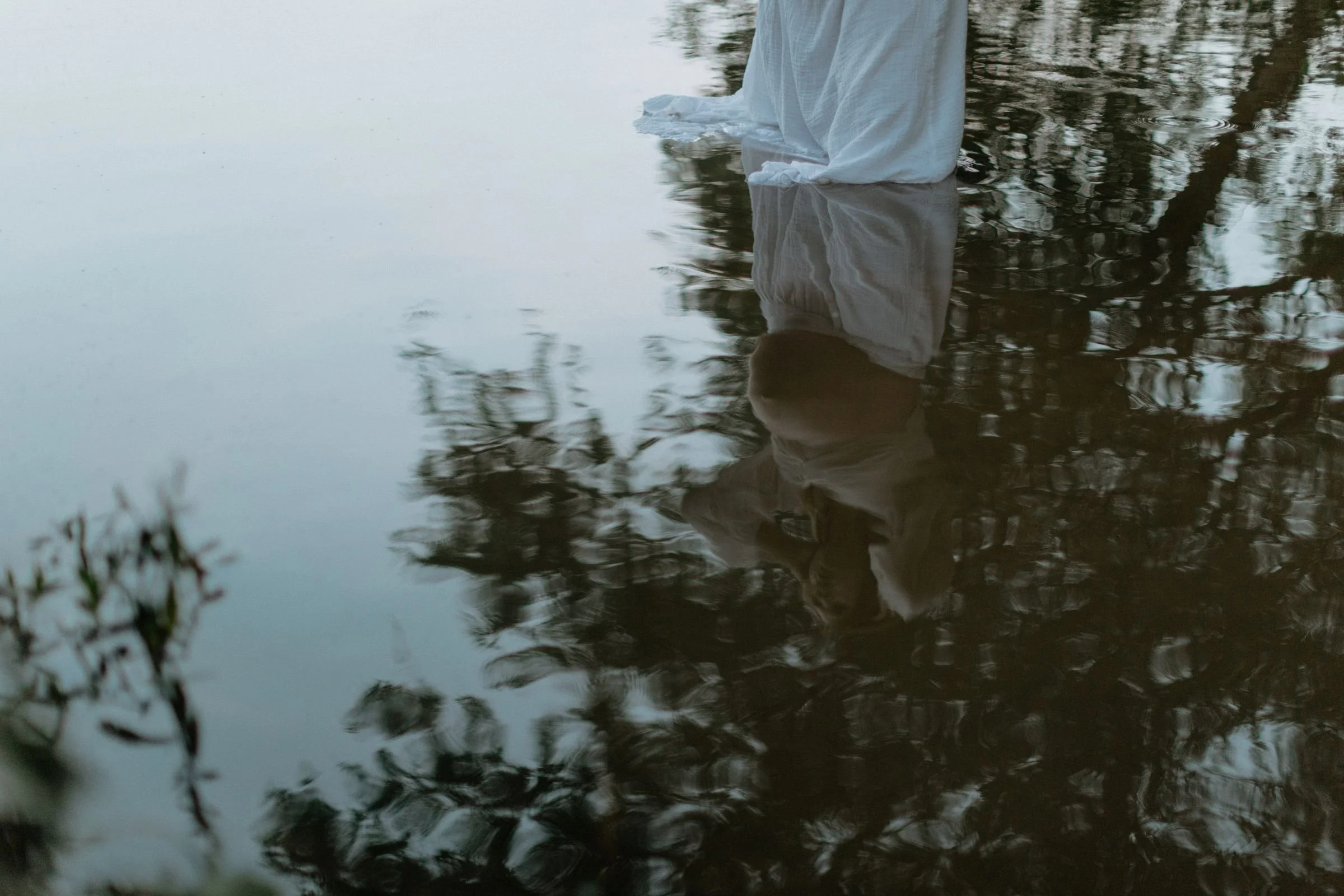 An artistic approach to a maternity session. A pregnant woman's reflection in the water.