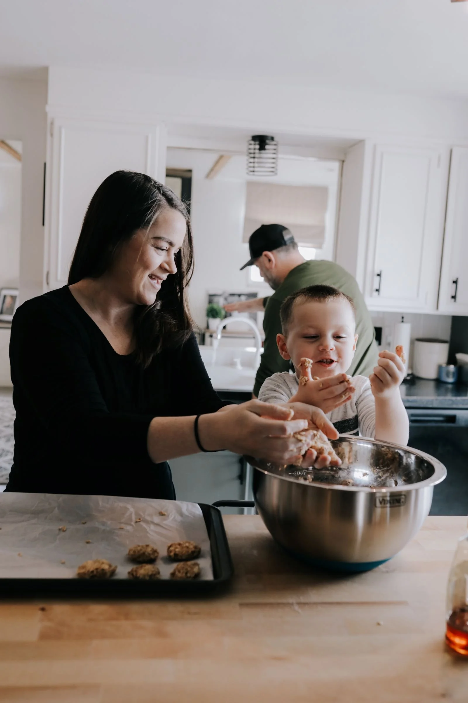 a mother and young sone making cookies and mixing batter in a large silver bowl