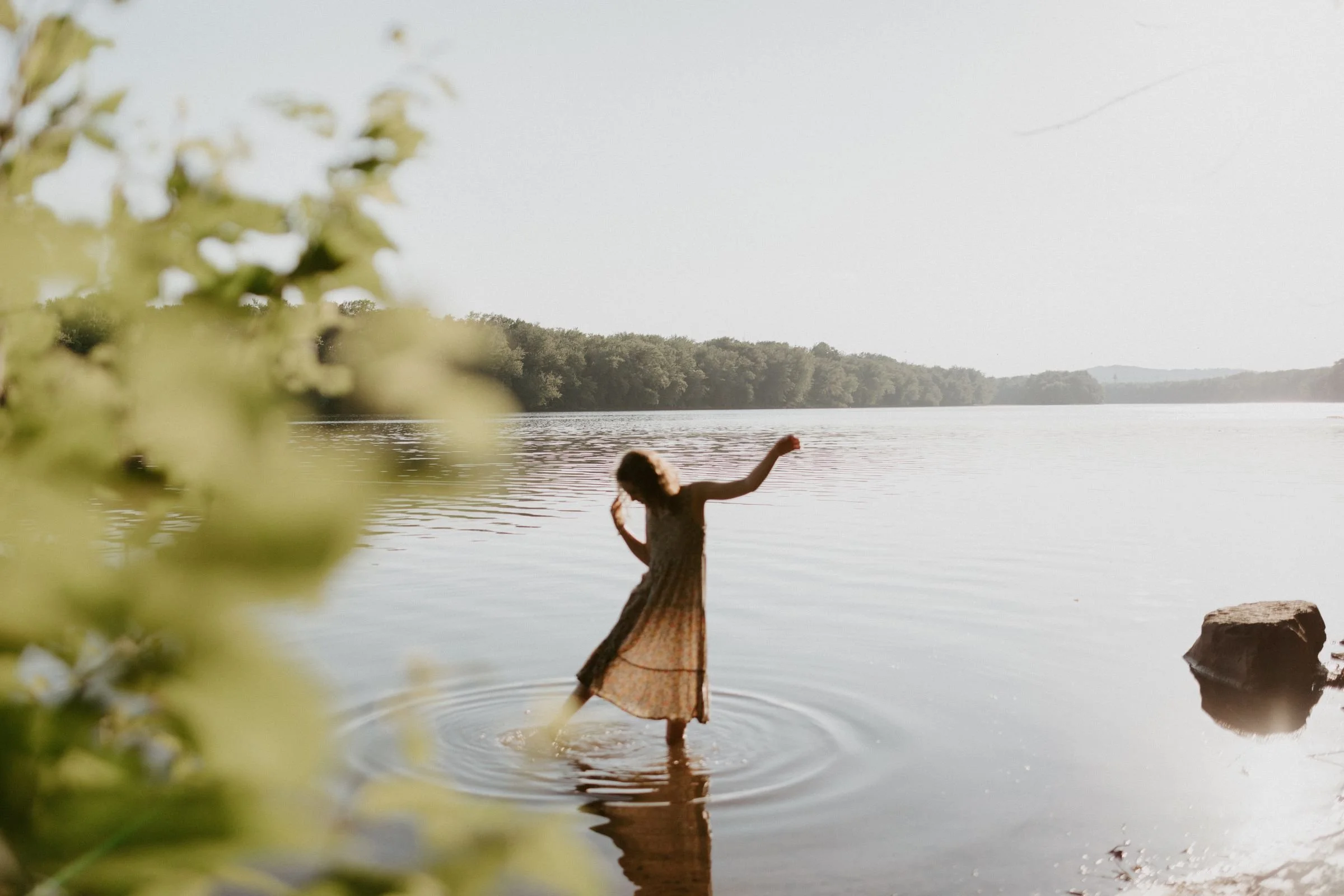 out of focus photograph of a young girl in a dress making ripples in the water of the Susquehanna River.