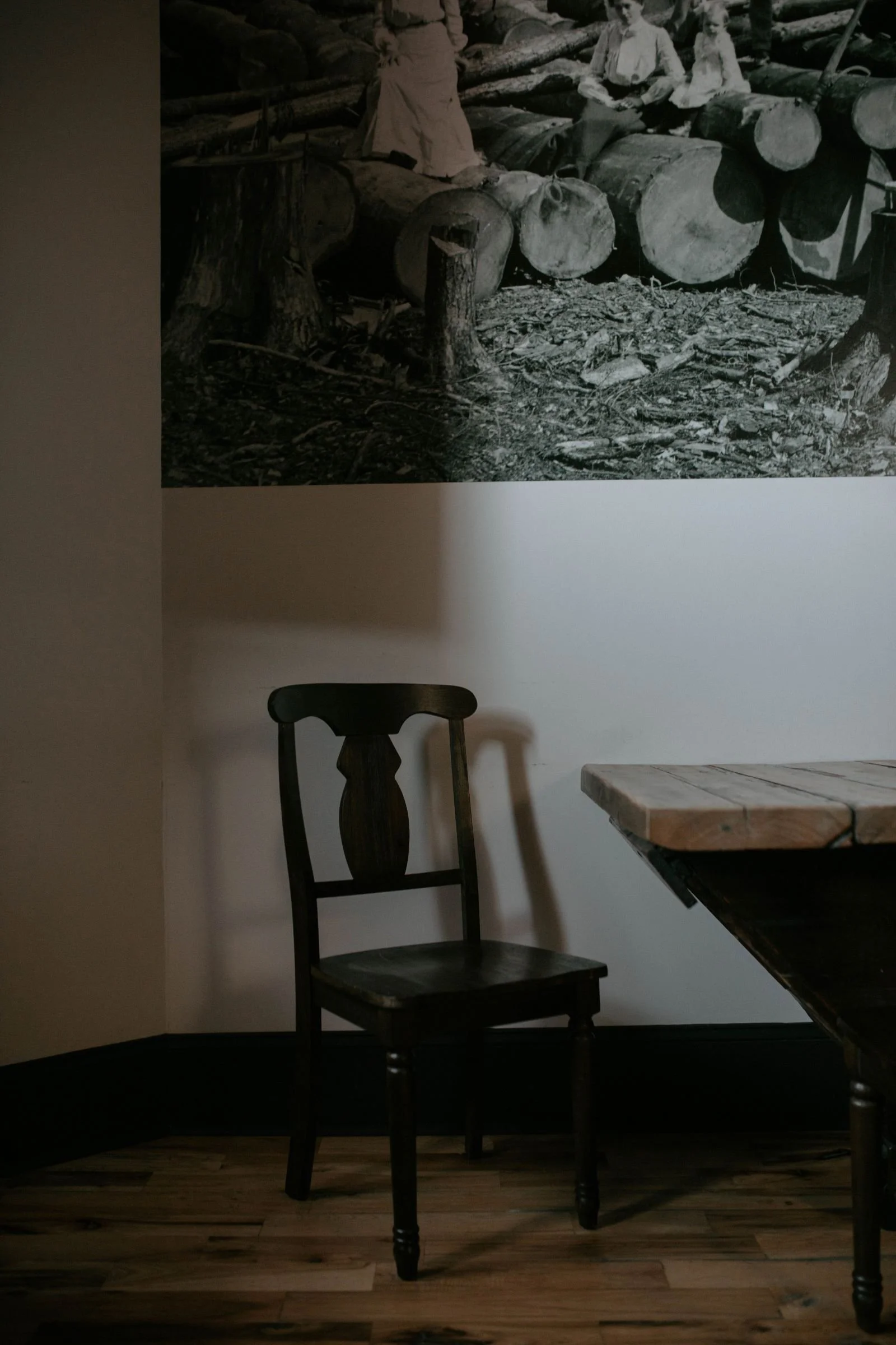 boutique hotel room with an empty chair, table and a photograph of the local lumber industry hanging on the wall