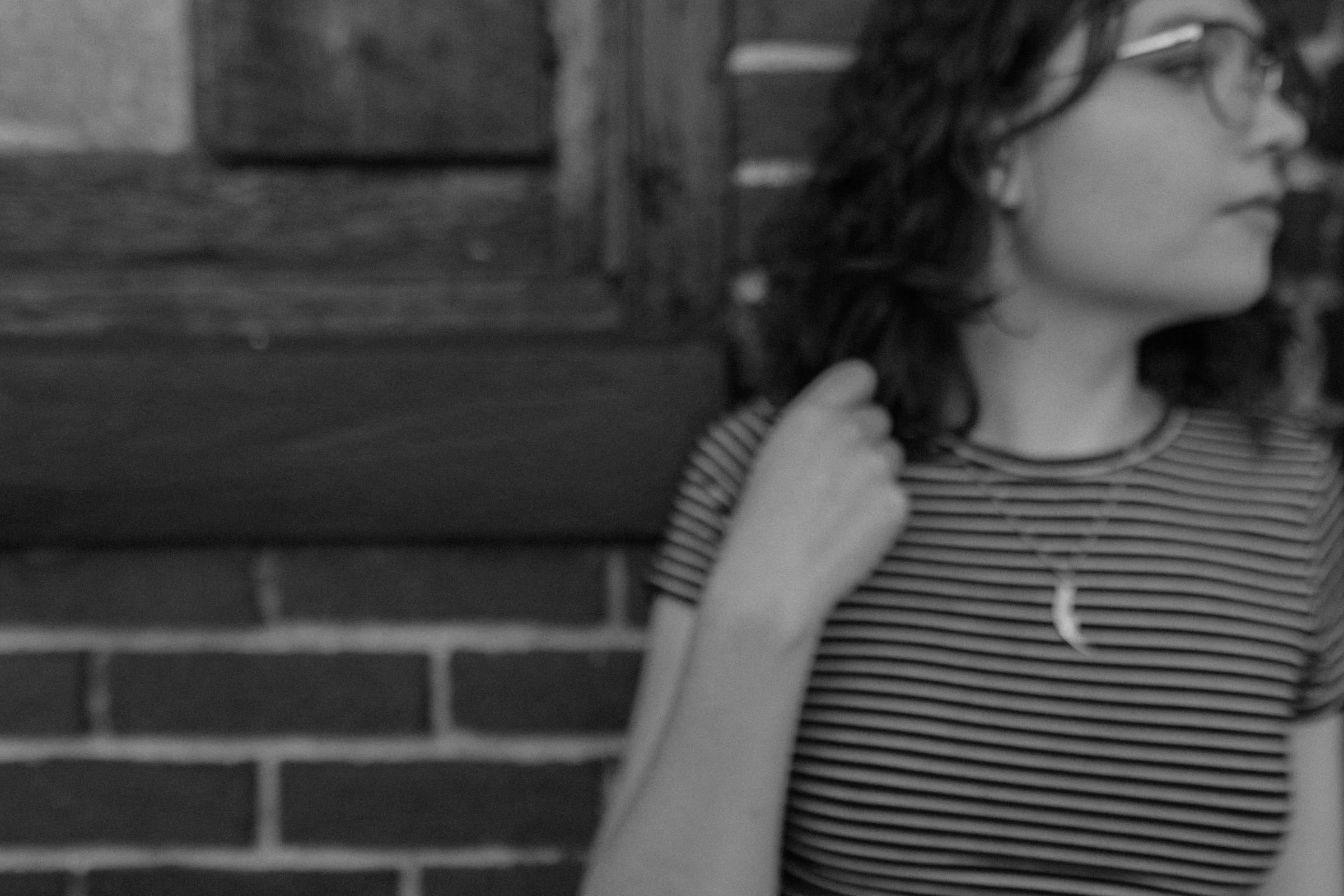 eighteen year old girl standing in front of a brick wall wearing a black and white striped shirt