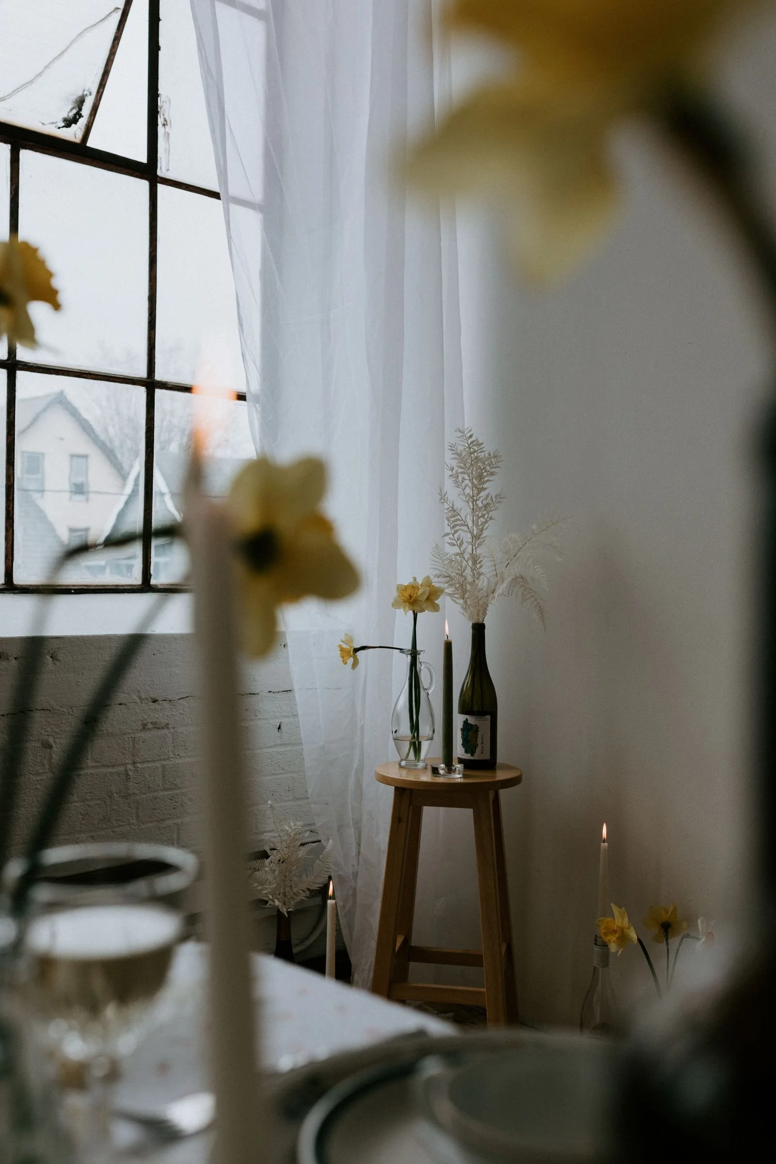 artfully staged wine bottle, candles and flowers in a white brick studio
