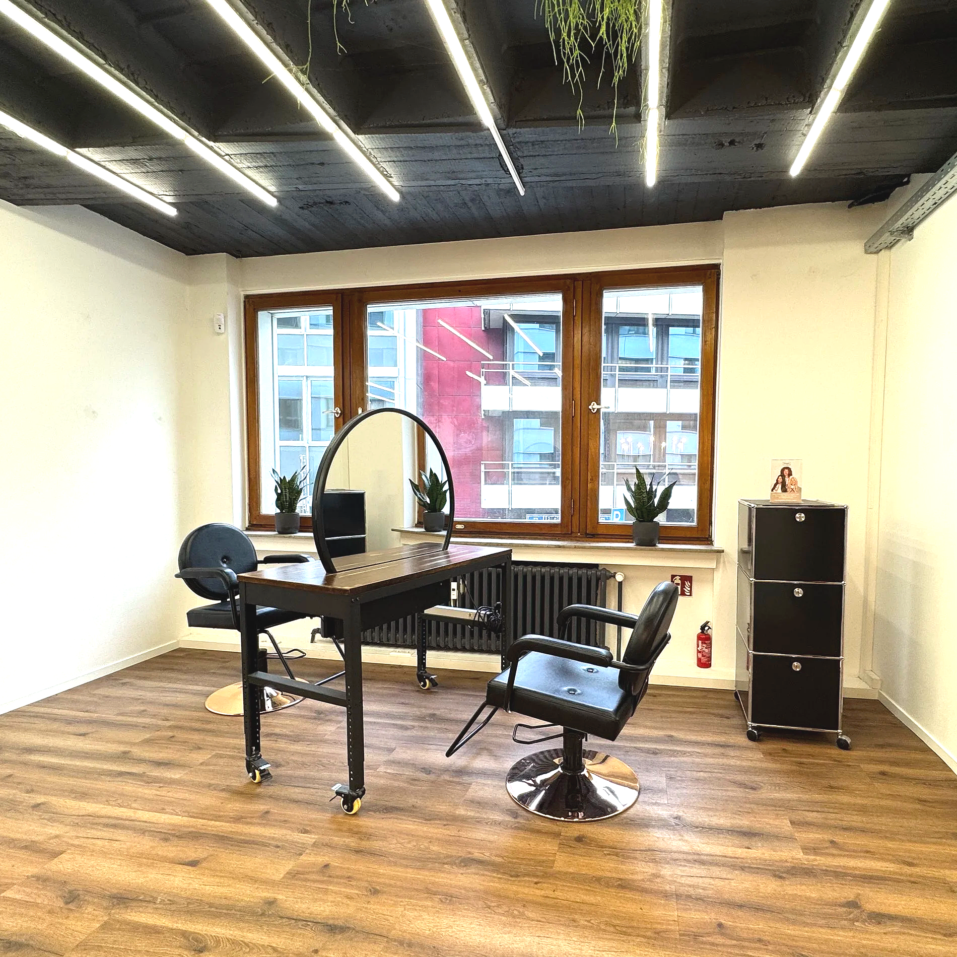 Boutique Studio Arbeitsplatz für Hair & Beauty Professionals.
Großer Spiegel, eleganter Stylingstuhl, warme Holzböden und markante Lichtakzente schaffen eine ruhige, hochwertige Studioatmosphäre.
