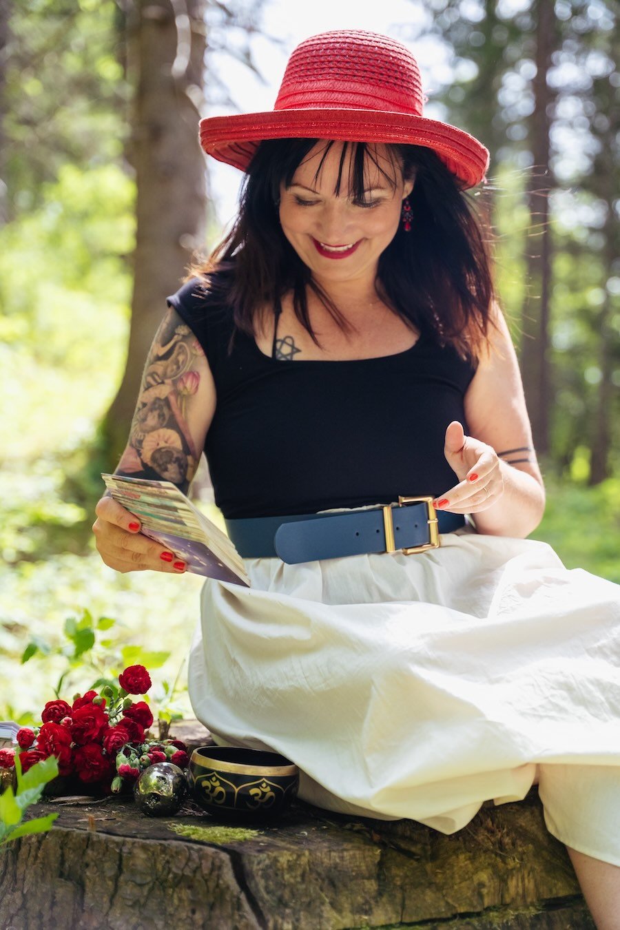 Alina mit rotem Hut sitzt auf einer Lichtung. 