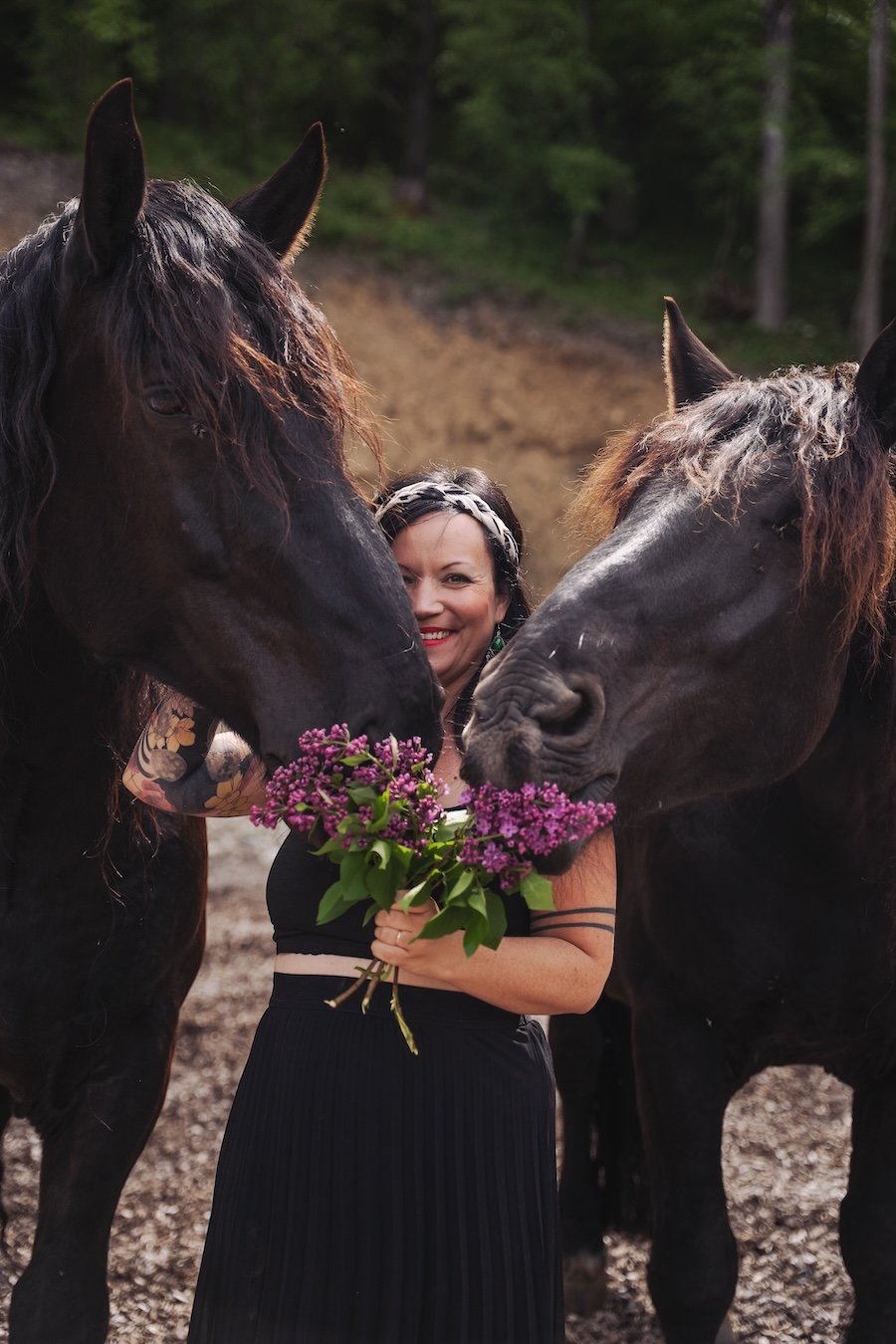 Alina mit violetten bLumen in der Hand zwischen zwei Pferden.