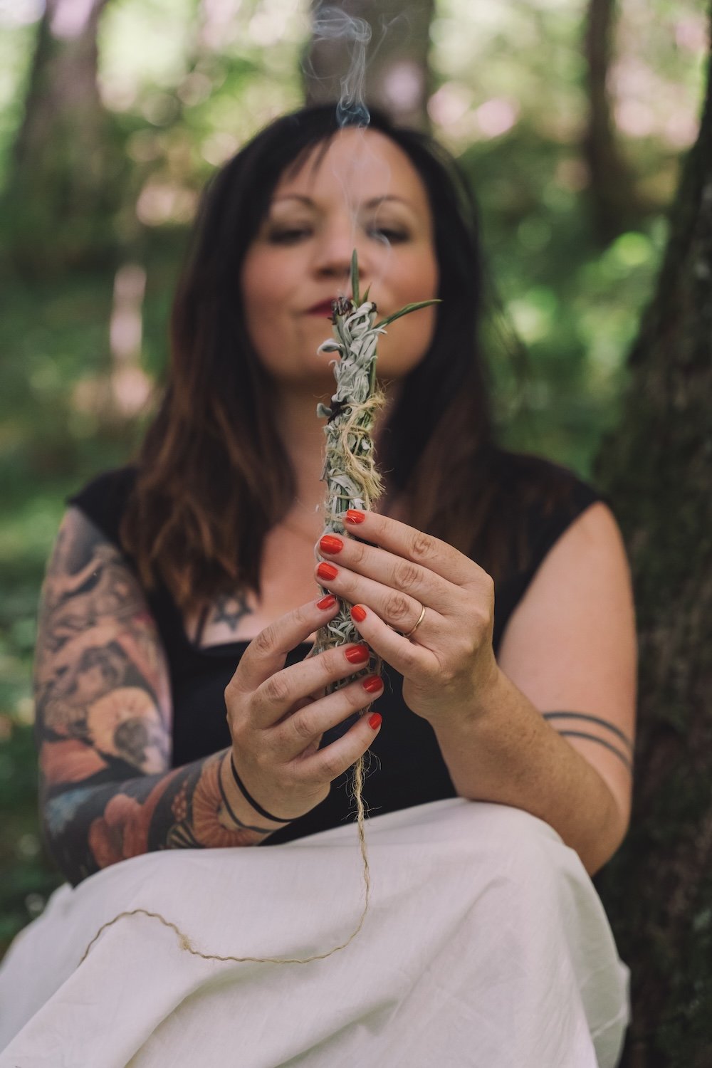 Alina hält mit geschlossenen Augen ein rauchendes Salbeibündel vor sich, Ritual zum Ankommen vor einem Reading.