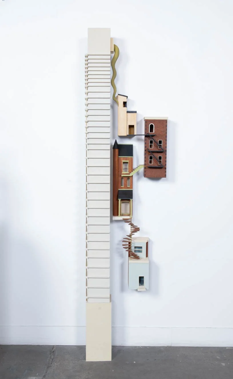 A sculpture made up of different architectural style buildings in Philadelphia. Made primarily out of wood.