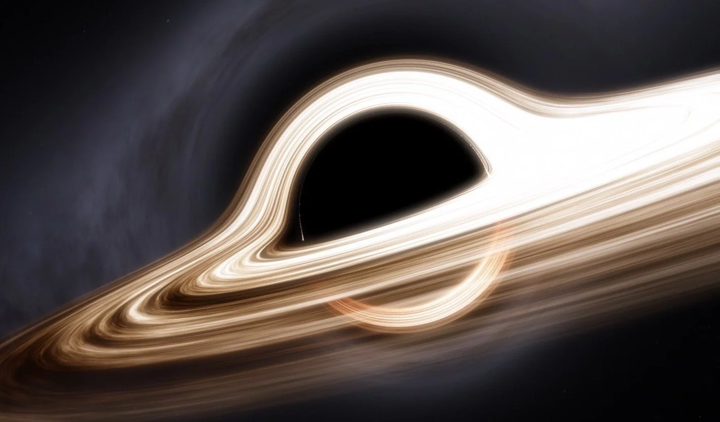 A photo of a black hole with glowing light rings around it, highlighting the event horizon, against a dark space background.