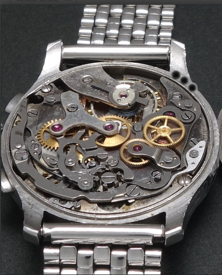 Close-up of a disassembled mechanical watch with visible gears and inner components.