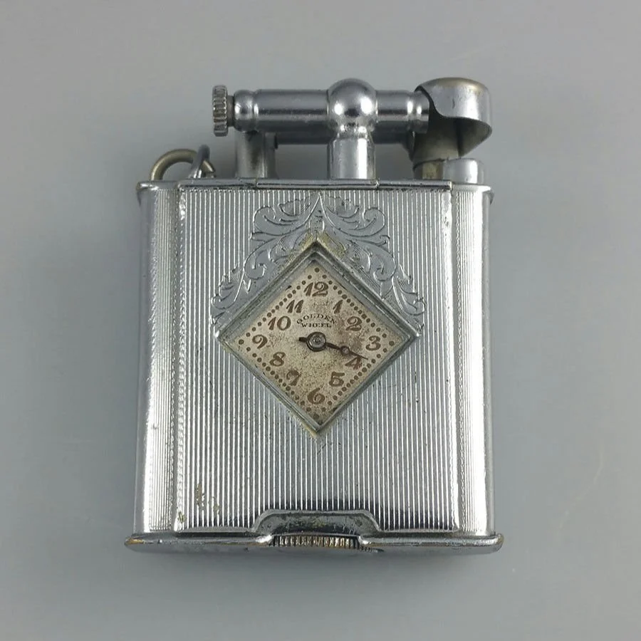 A vintage silver cigarette lighter with an embedded clock in the center showing the time as 2:19.
