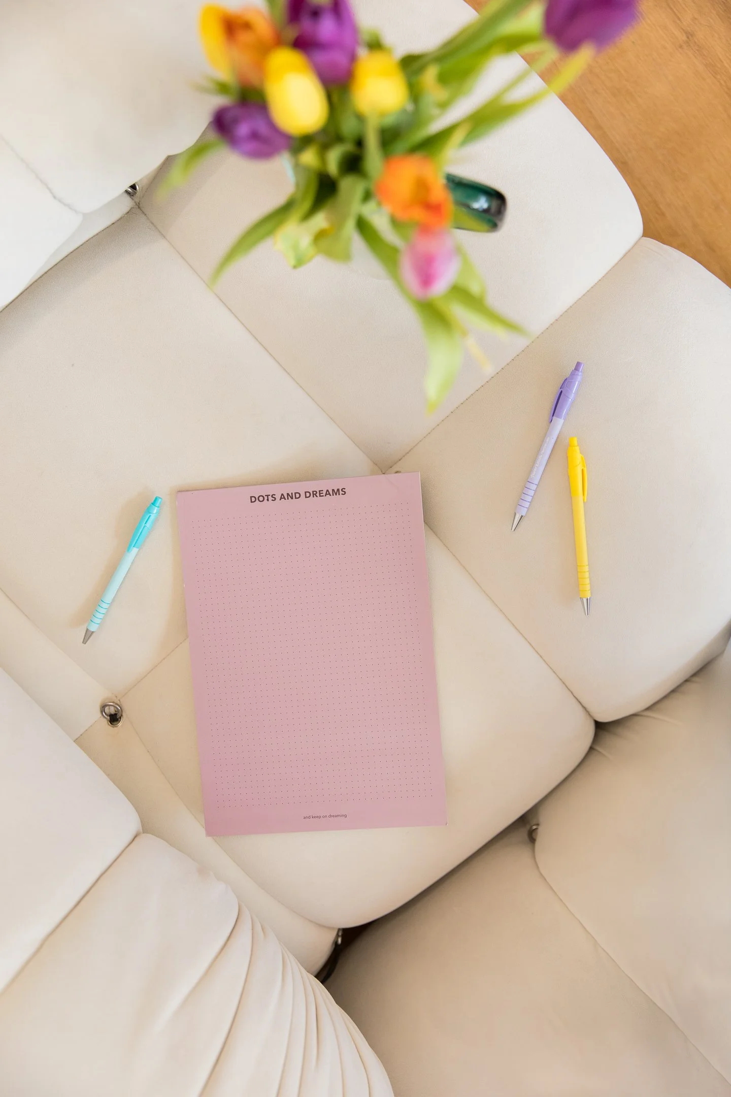 Image of a purple notepad and pens, on a sofa cushion