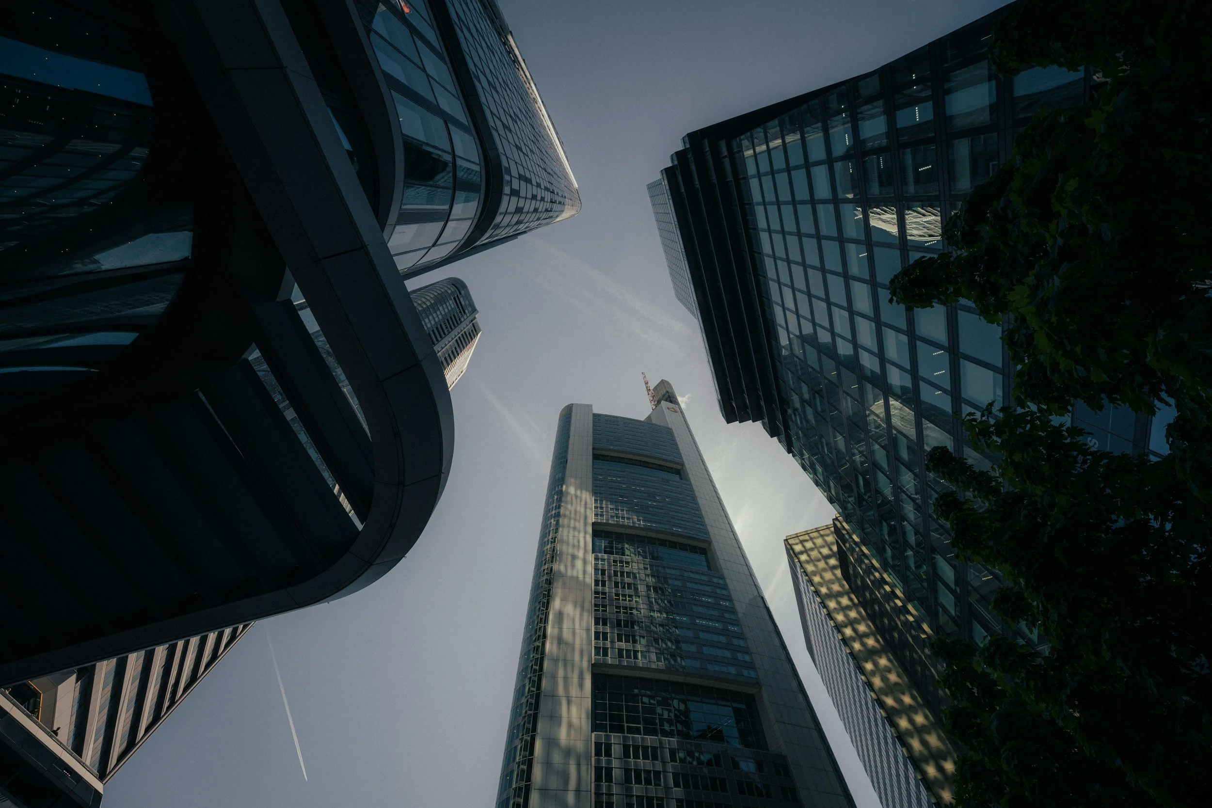 Looking up at tall glass skyscrapers and modern buildings in an urban city at dusk.