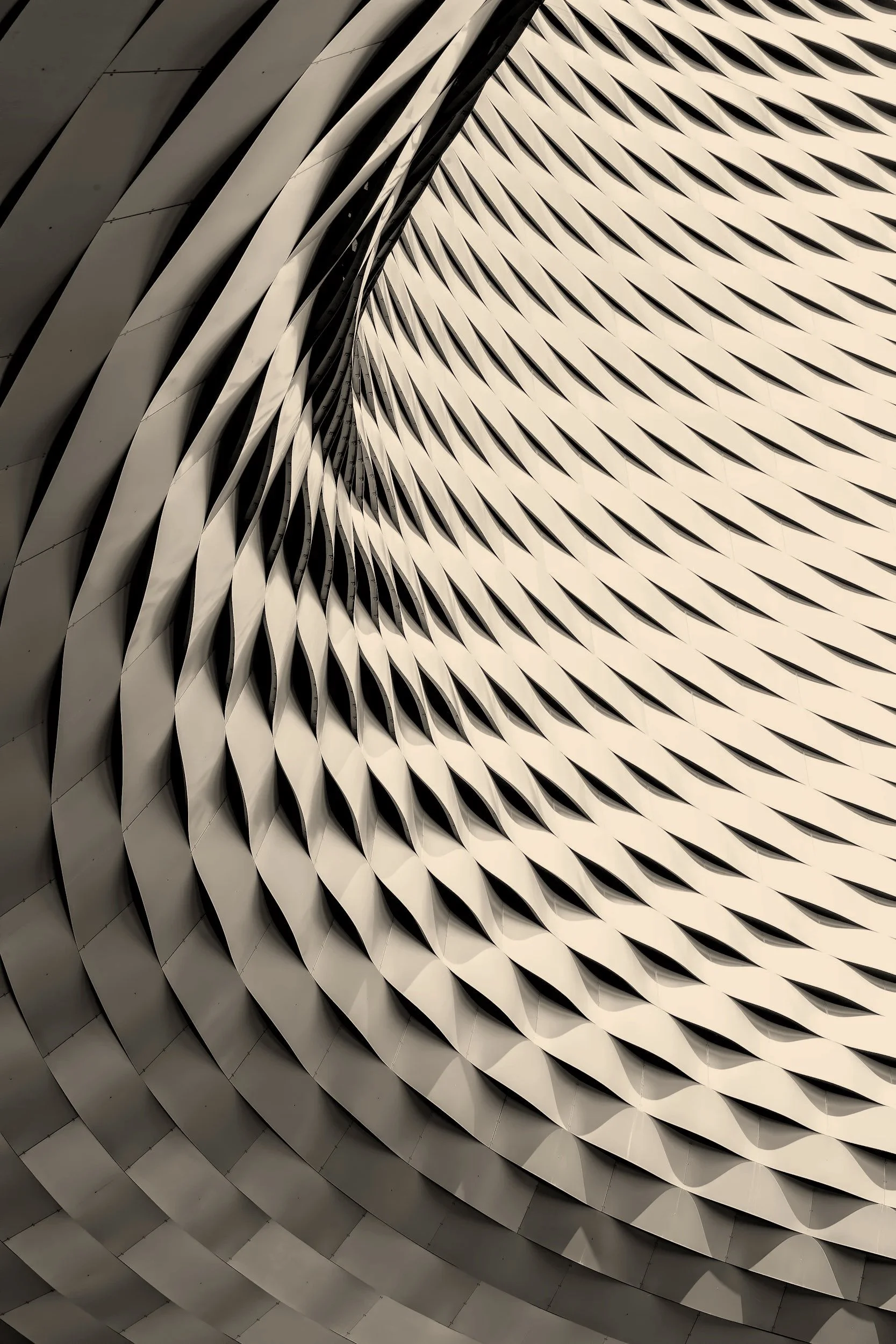 Close-up of a modern architectural structure with curved, layered, white panels creating a swirling pattern.