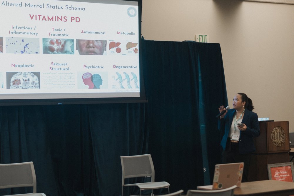 A presenter speaks beside slides during a conference session