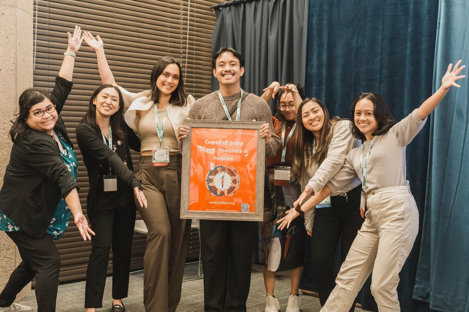 Seven CYFAM conference attendees cheer together around a framed certificate