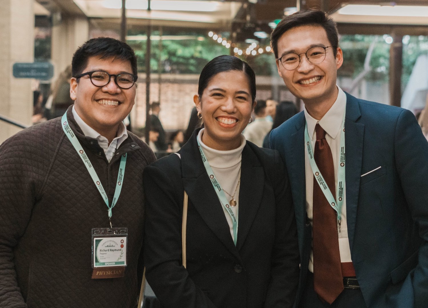 Three CYFAM conference attendees with lanyards smile together