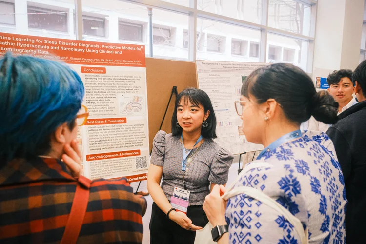 A student presents her research poster to attendees.