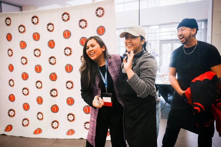 CYFAM volunteers share a laugh in front of the conference backdrop.