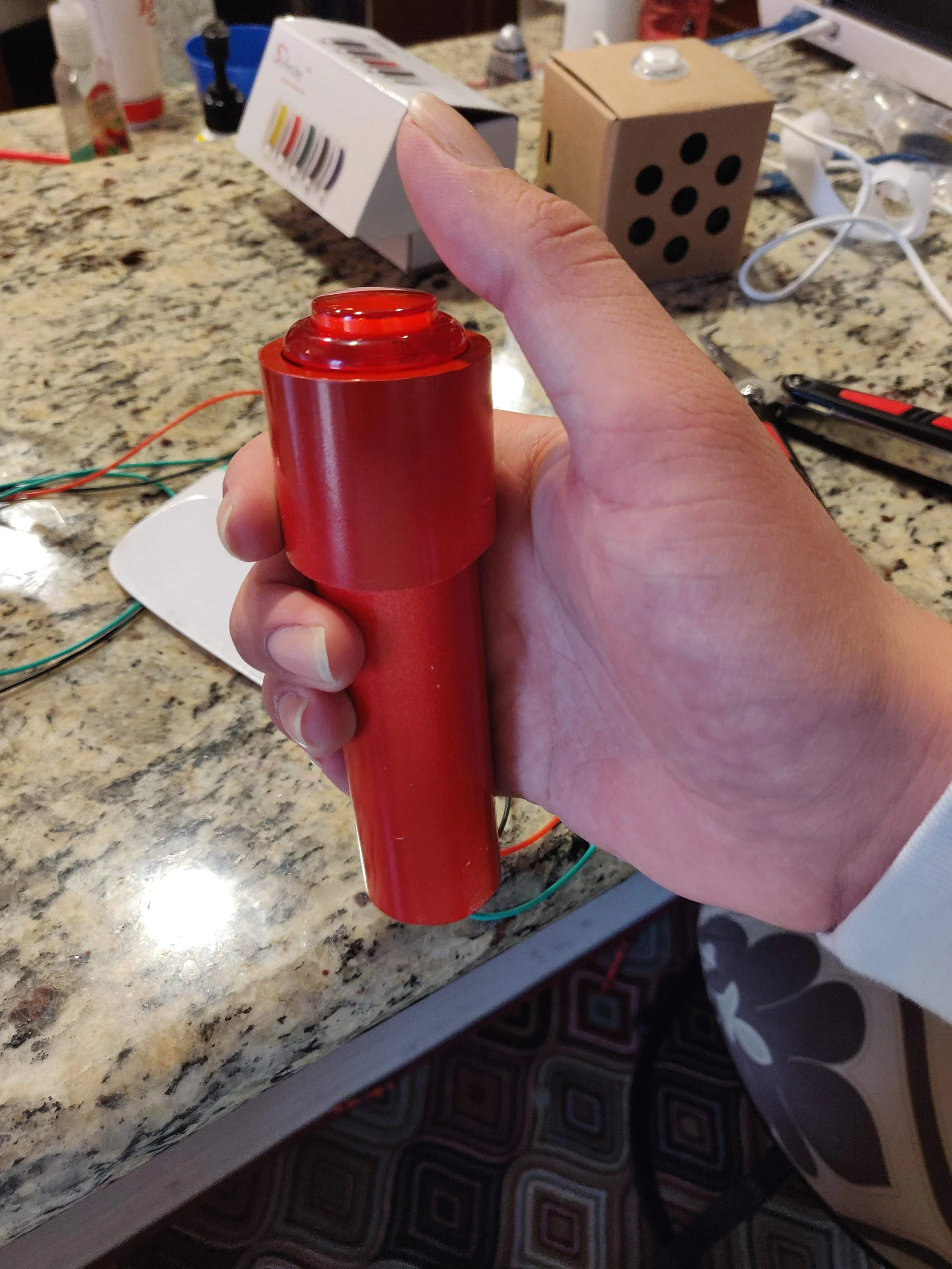 Red handheld signaling device or buzzer.