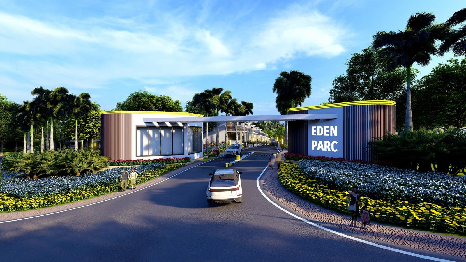 entrance gate to Eden Parc with modern buildings, lush landscaping, and people walking near the road.