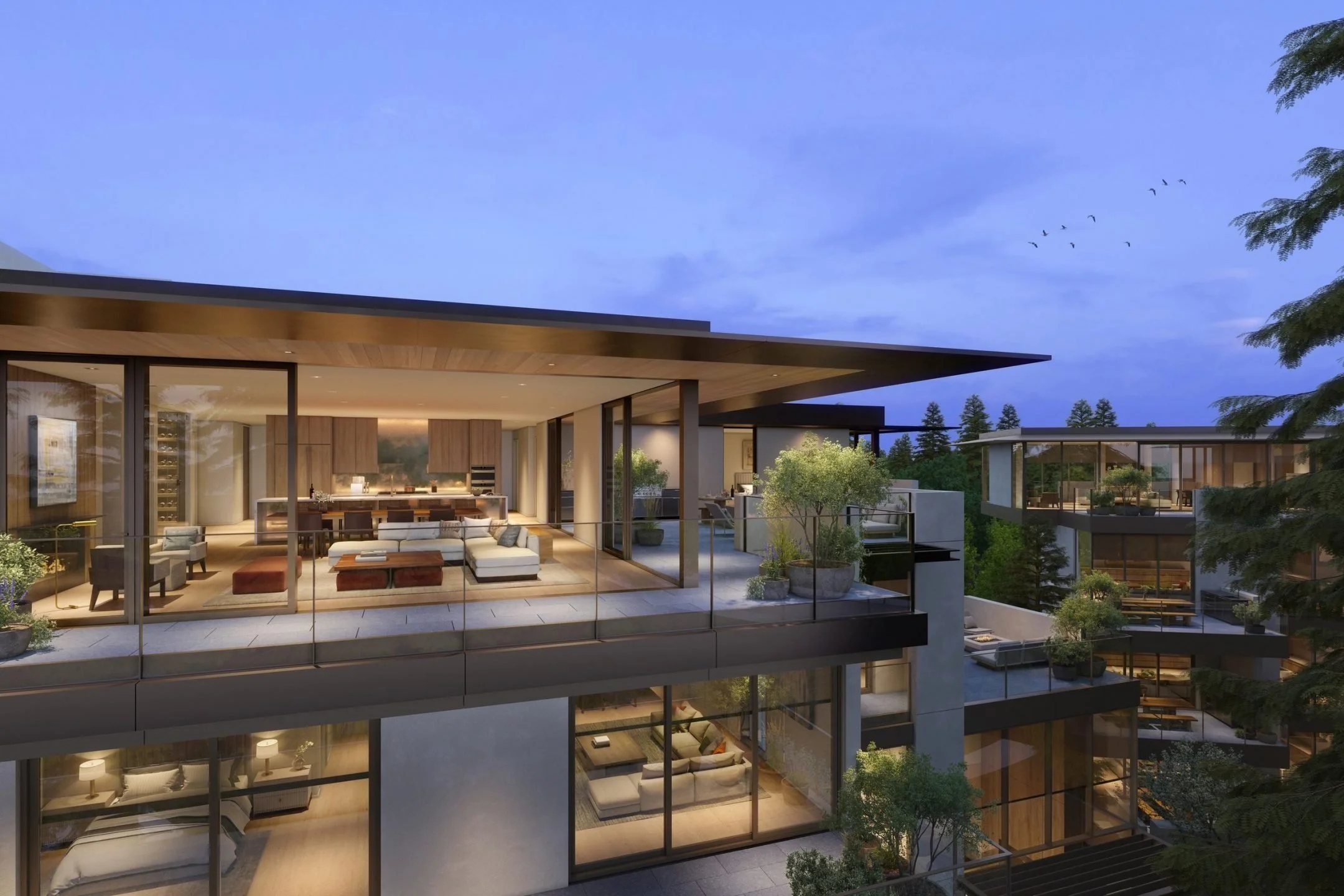 Modern multi-story apartment building at dusk with large glass windows, open living spaces with furniture, and outdoor terraces with plants and trees.