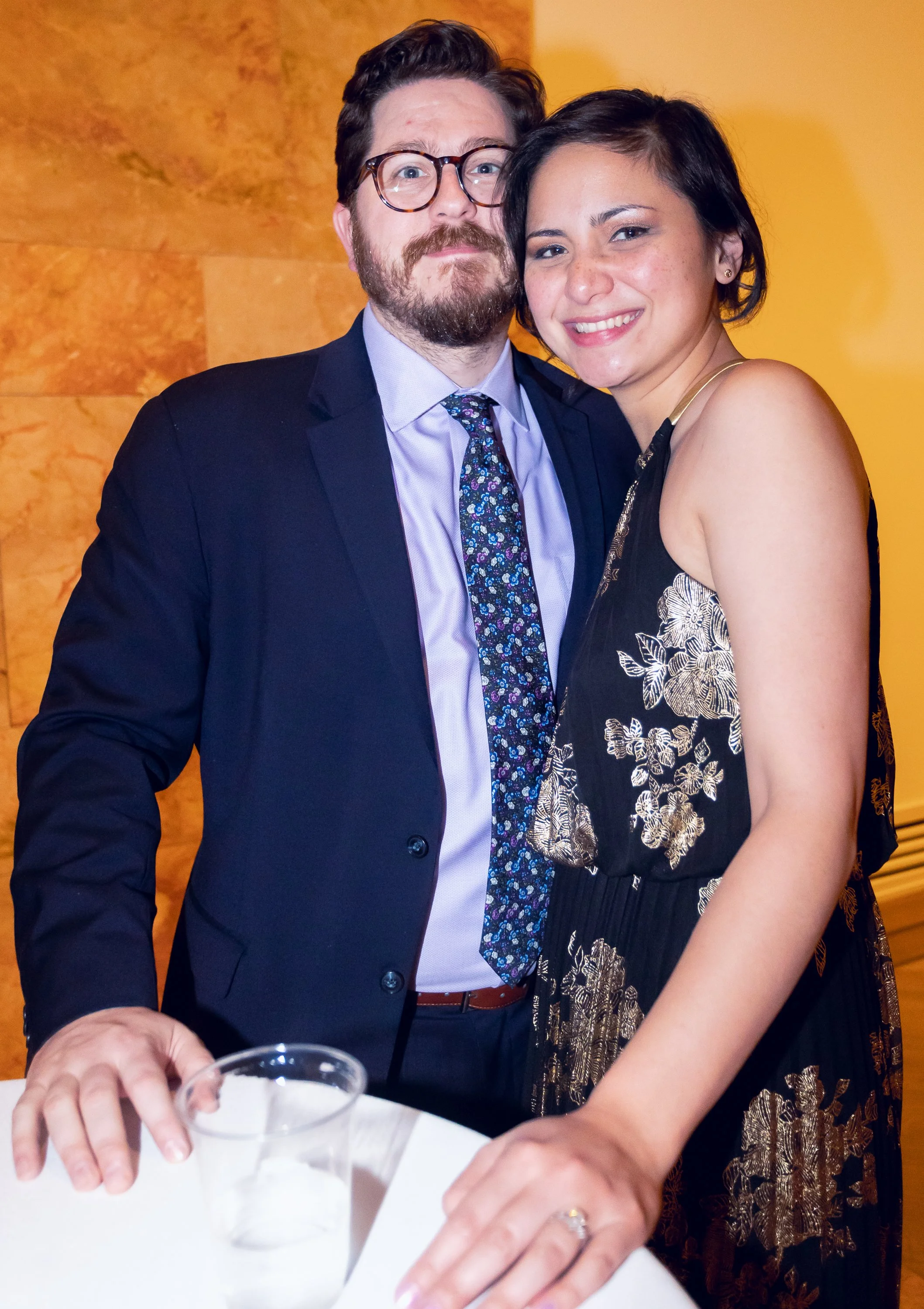 A man in glasses and a woman are smiling and posing for a photo at a formal event.