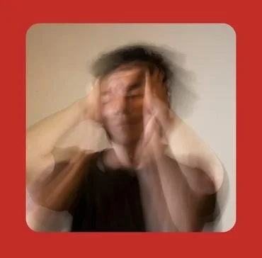 A blurred man holding his head with both hands, representing overwhelming anxiety, racing thoughts, and emotional distress, highlighting anxiety counselling support for gay, bisexual, queer, and LGBTQ+ men at Bent Couch.