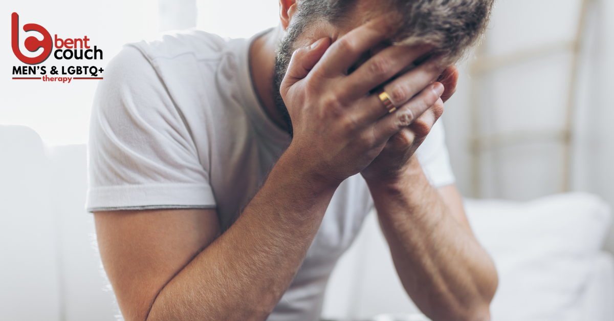 A man sits with his head in his hands, showing emotional distress and grief, representing the need for trauma and grief support and gentle self care during difficult times.