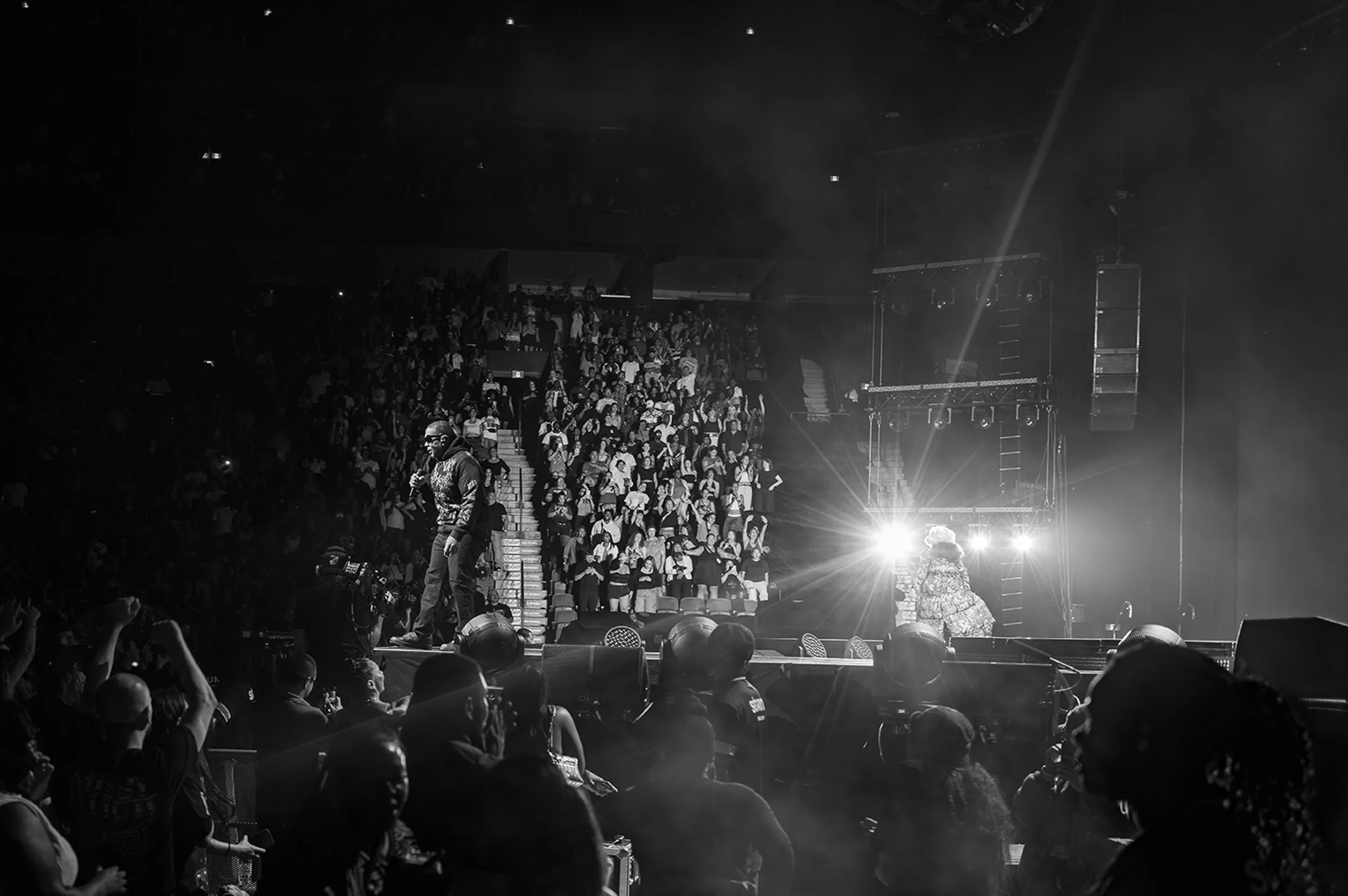 Black and white photo of a concert stage with performers and an audience in a theater setting.