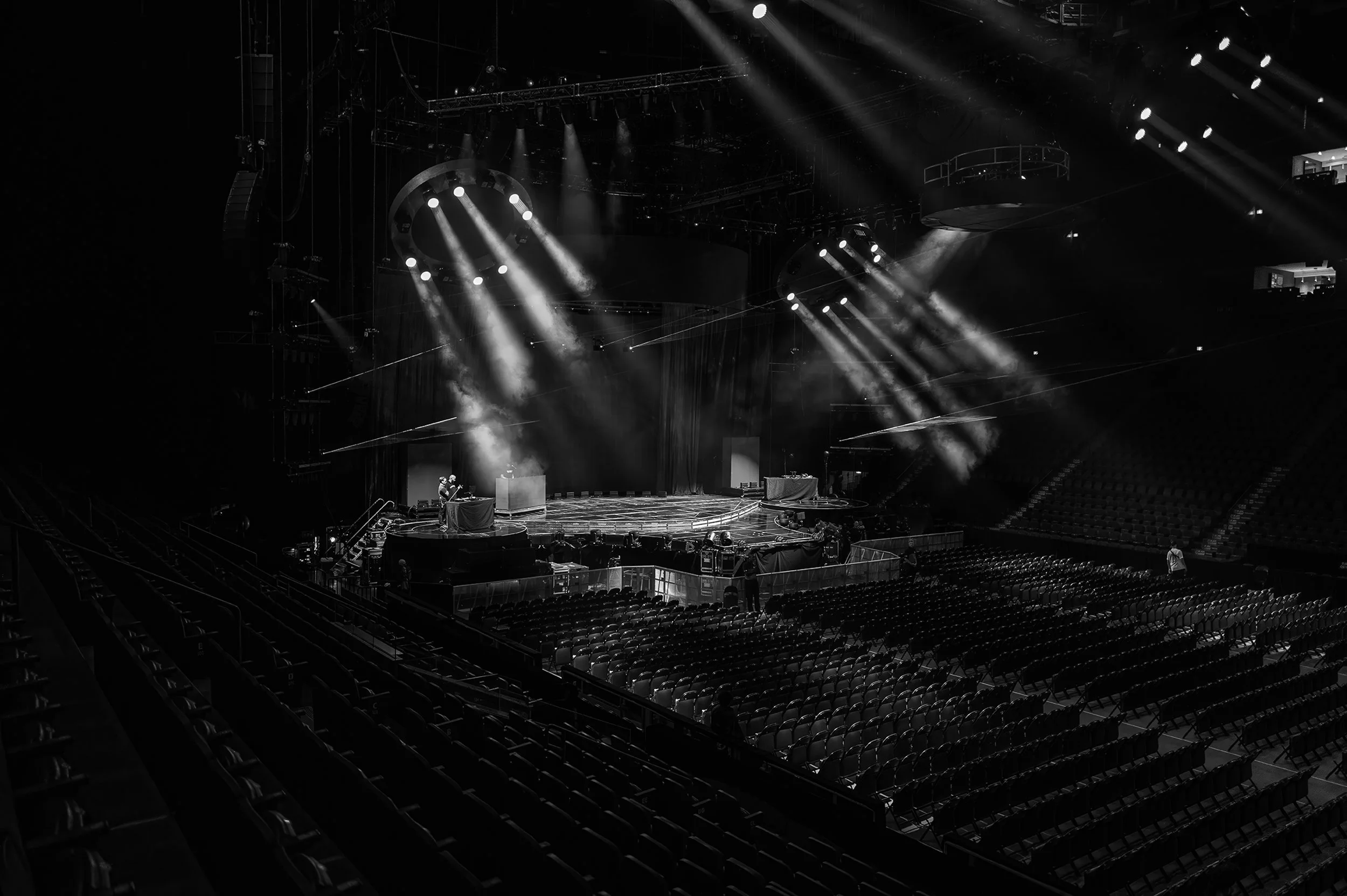 Empty concert arena with a stage, bright spotlights, and rows of empty seats.