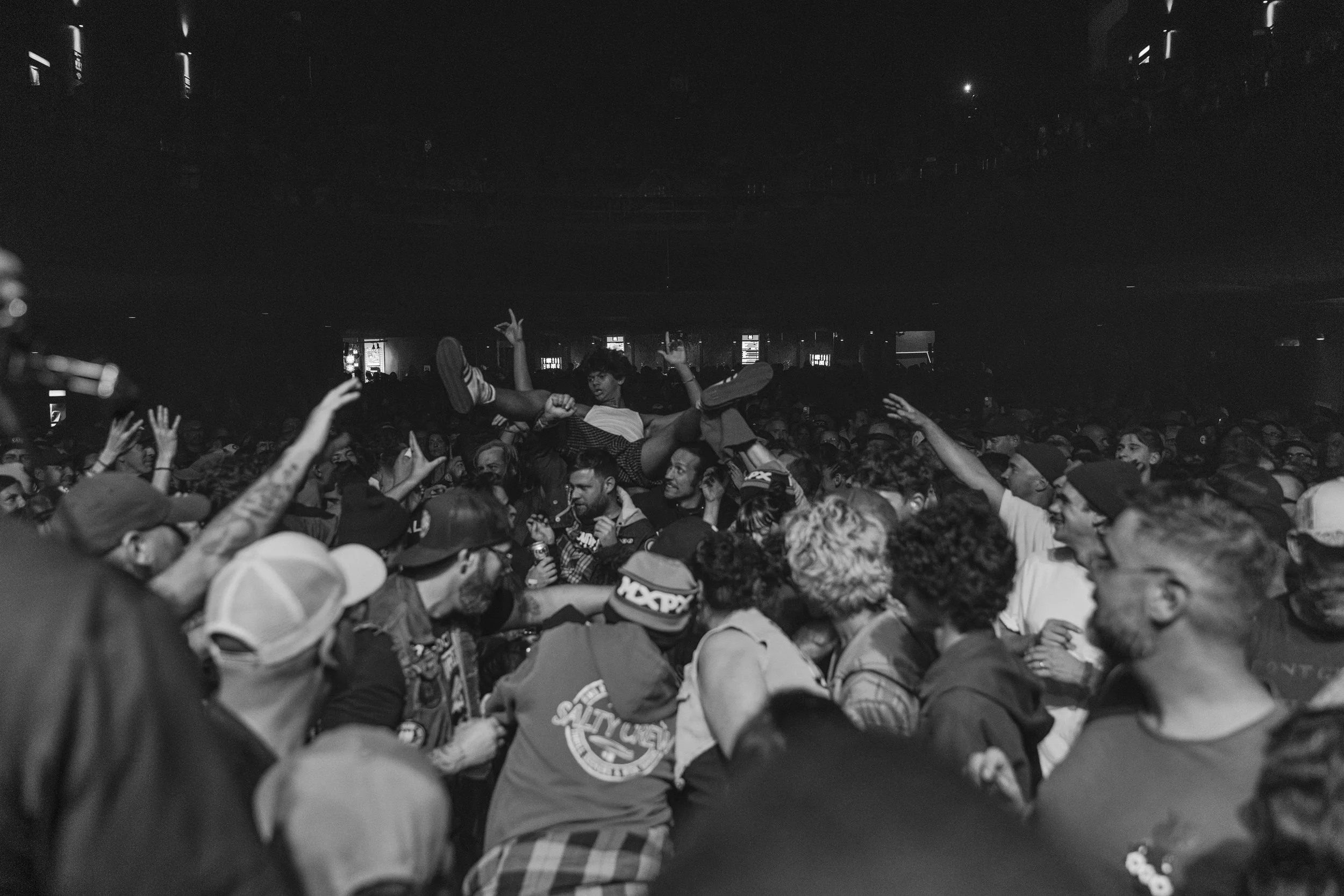 Crowd at a concert with a person crowd surfing in the middle.