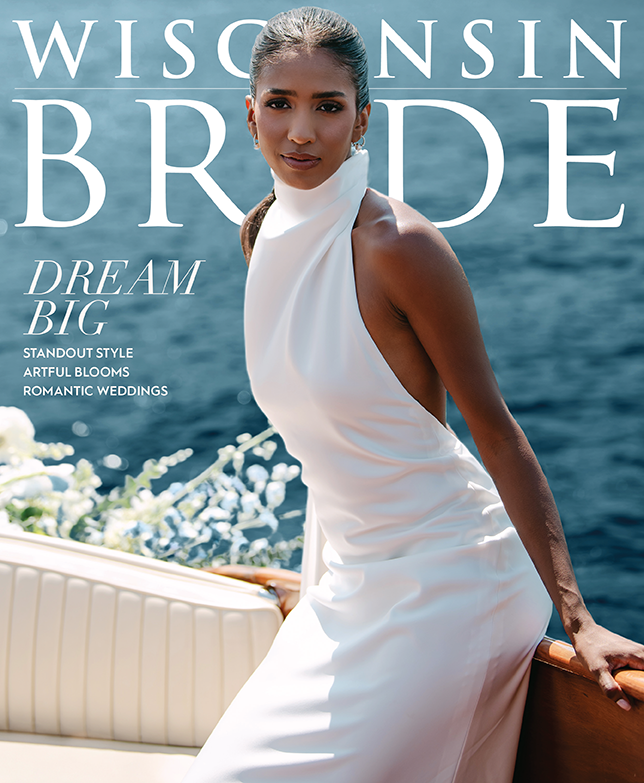 A woman in a white dress posing on a boat with water in the background, promoting Wisconsin bride magazine with the headline 'Dream Big'.