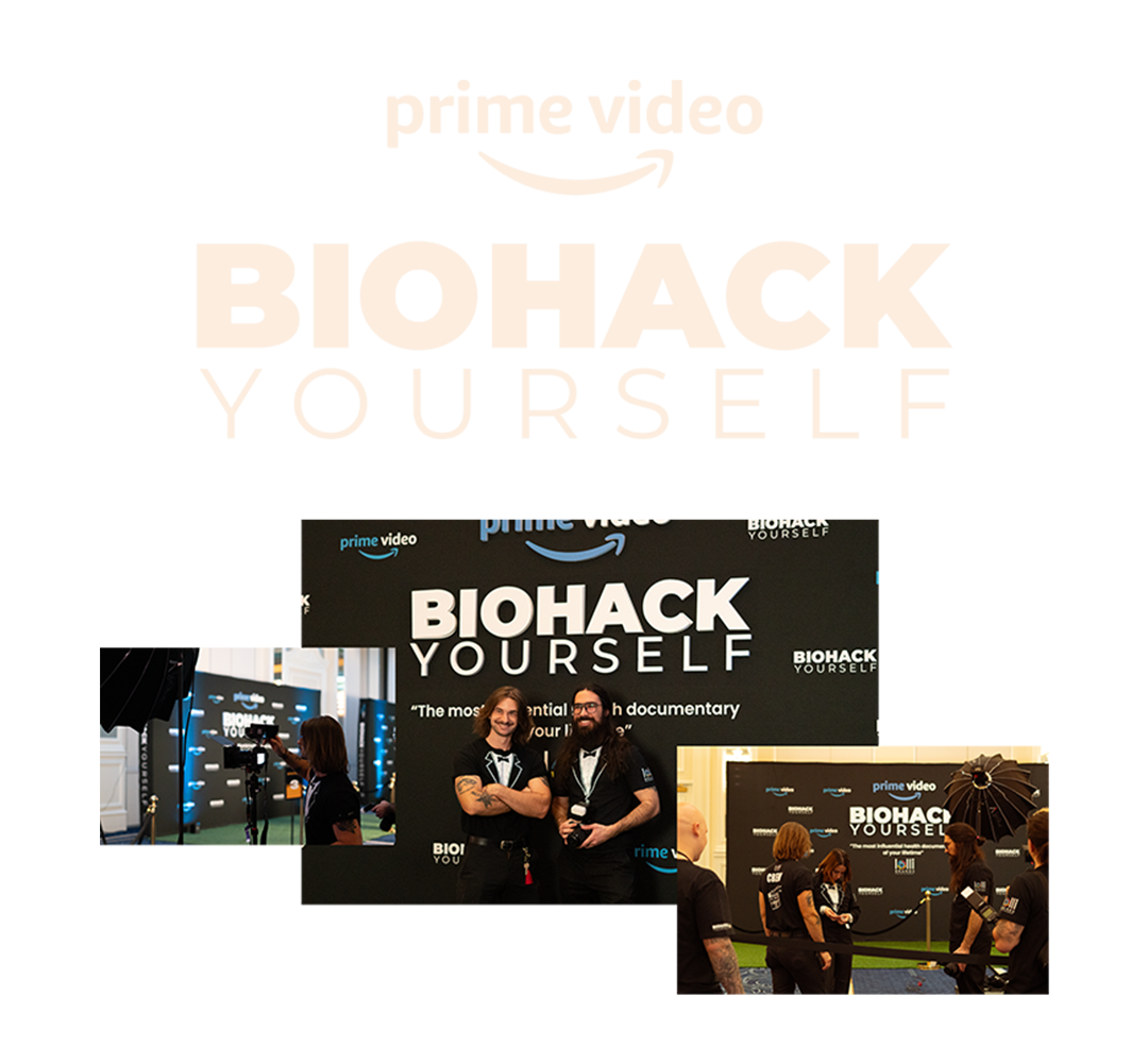 People attending the premiere of the documentary 'Biohack Yourself' at an event with a large backdrop displaying the title and logos of Amazon Prime Video and Biohack Yourself.