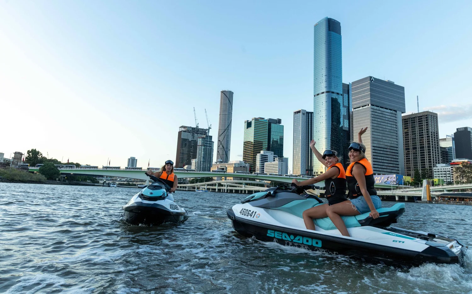 Jetski riders on the Brisbane River with the city skyline