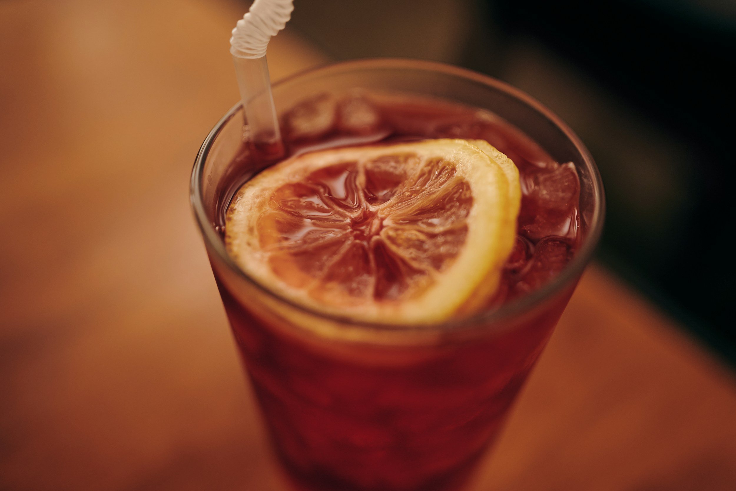 A glass of iced tea with a lemon slice and a straw.