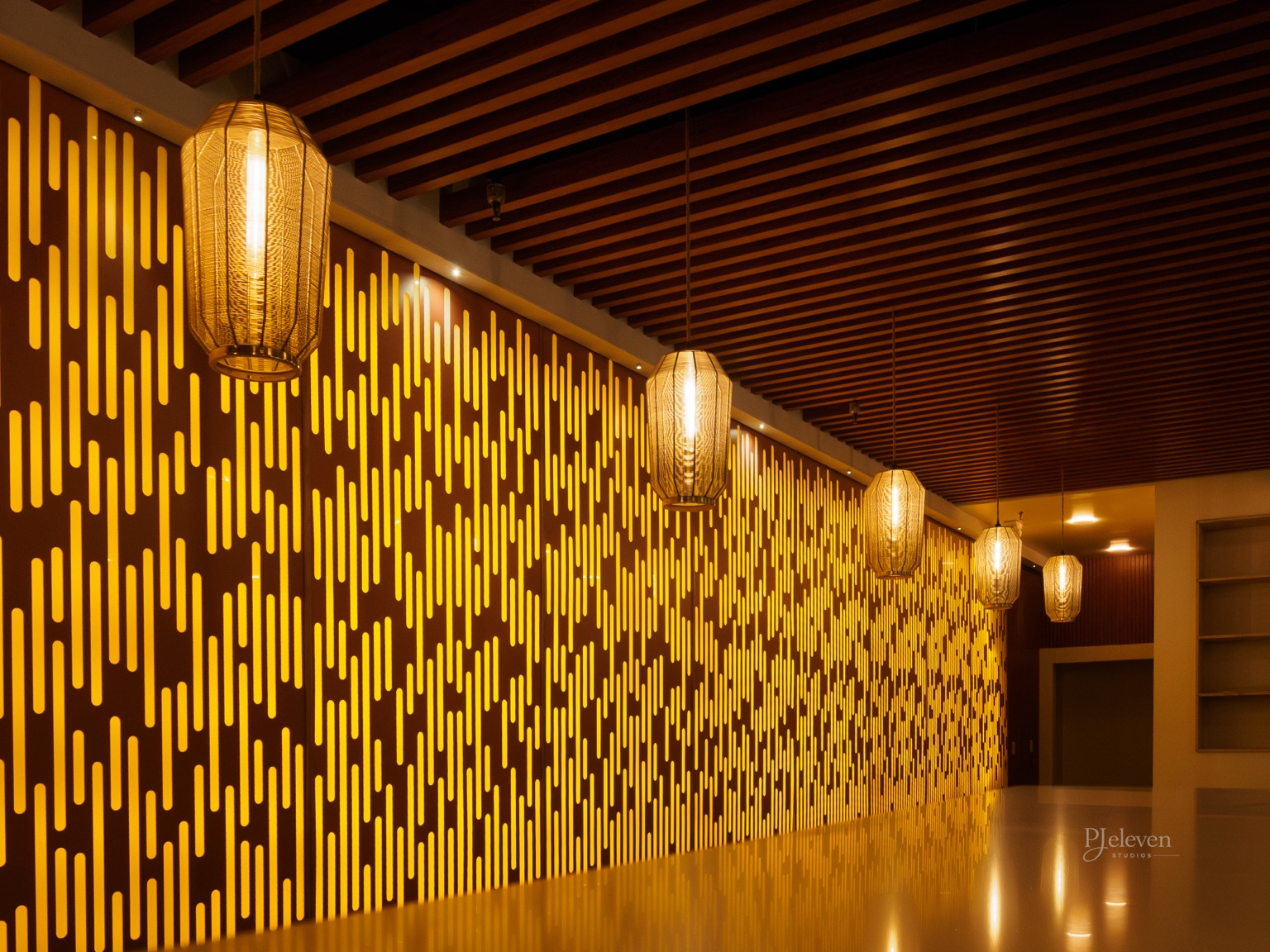 Interior hallway with decorative yellow and brown wall panels, wooden ceiling beams, and hanging pendant lights.