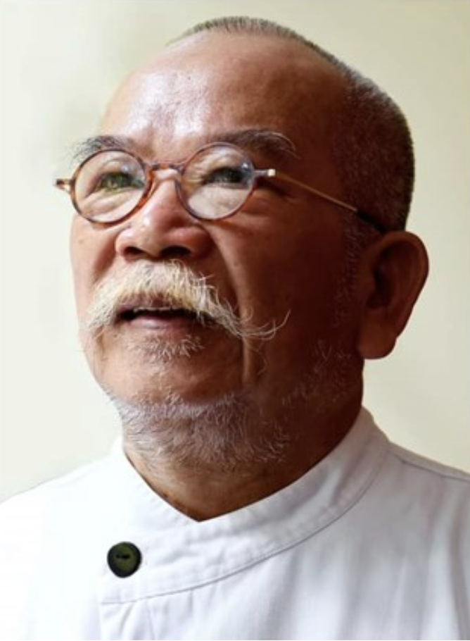 Pho Thin Logo Close-up of an elderly man with glasses and a mustache wearing a white chef coat, smiling and looking slightly to the side.
