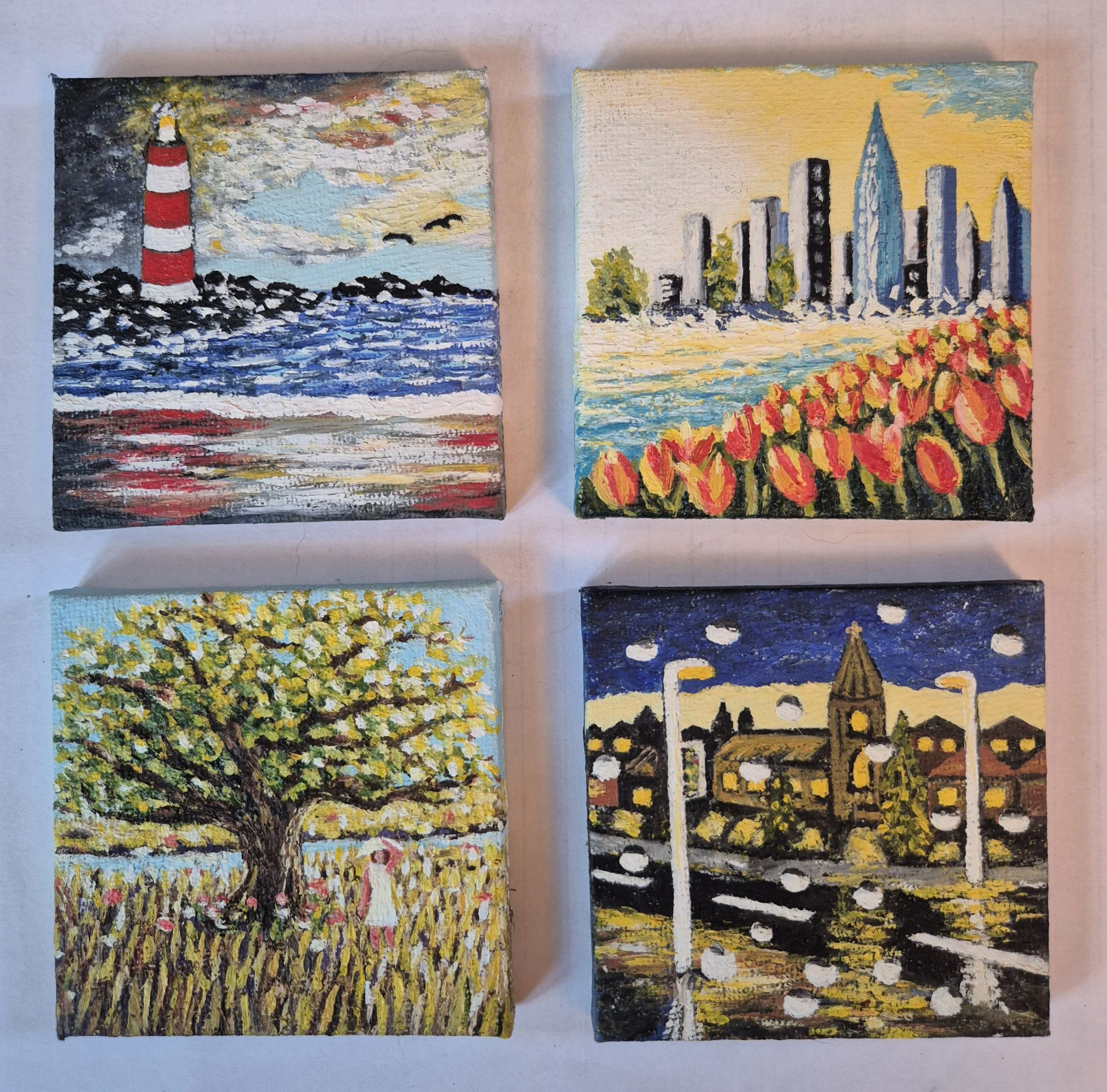 Set of mniature oil paintings featuring a lighthouse, cityscape, and nature