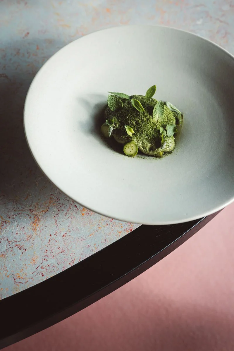 Green dish with herbs and vegetables served on a white plate Restaurant Putaine, Rotterdam, The Netherlands Photography Sophia van den Hoek