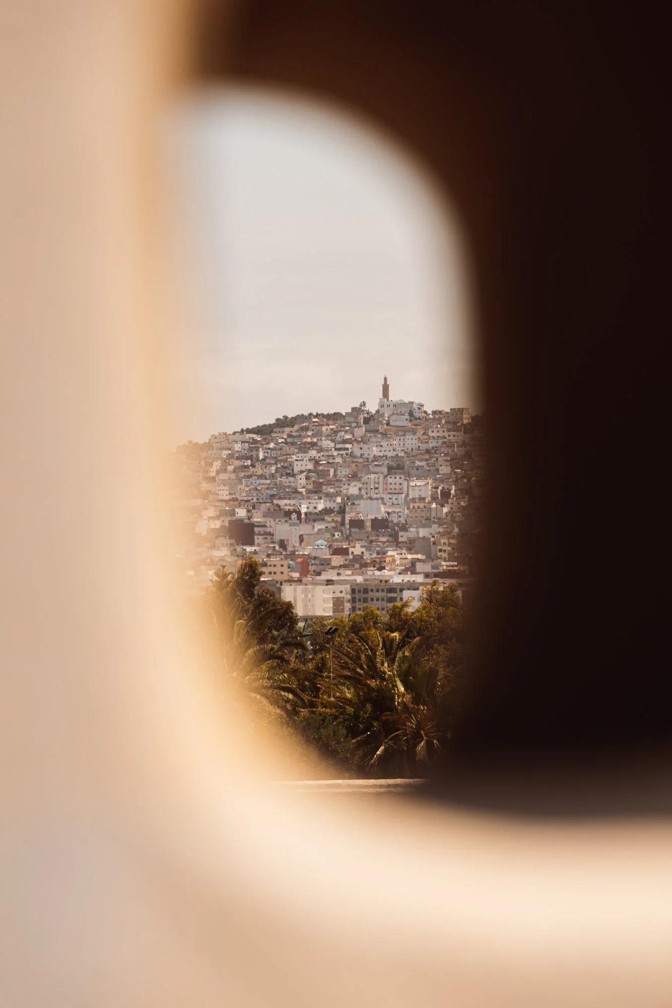 Cityscape of San Francisco with a hill and a lighthouse on top, viewed through a narrow opening. Royal Mansour Tamuda Bay Morocco. Photography Sophia van den Hoek