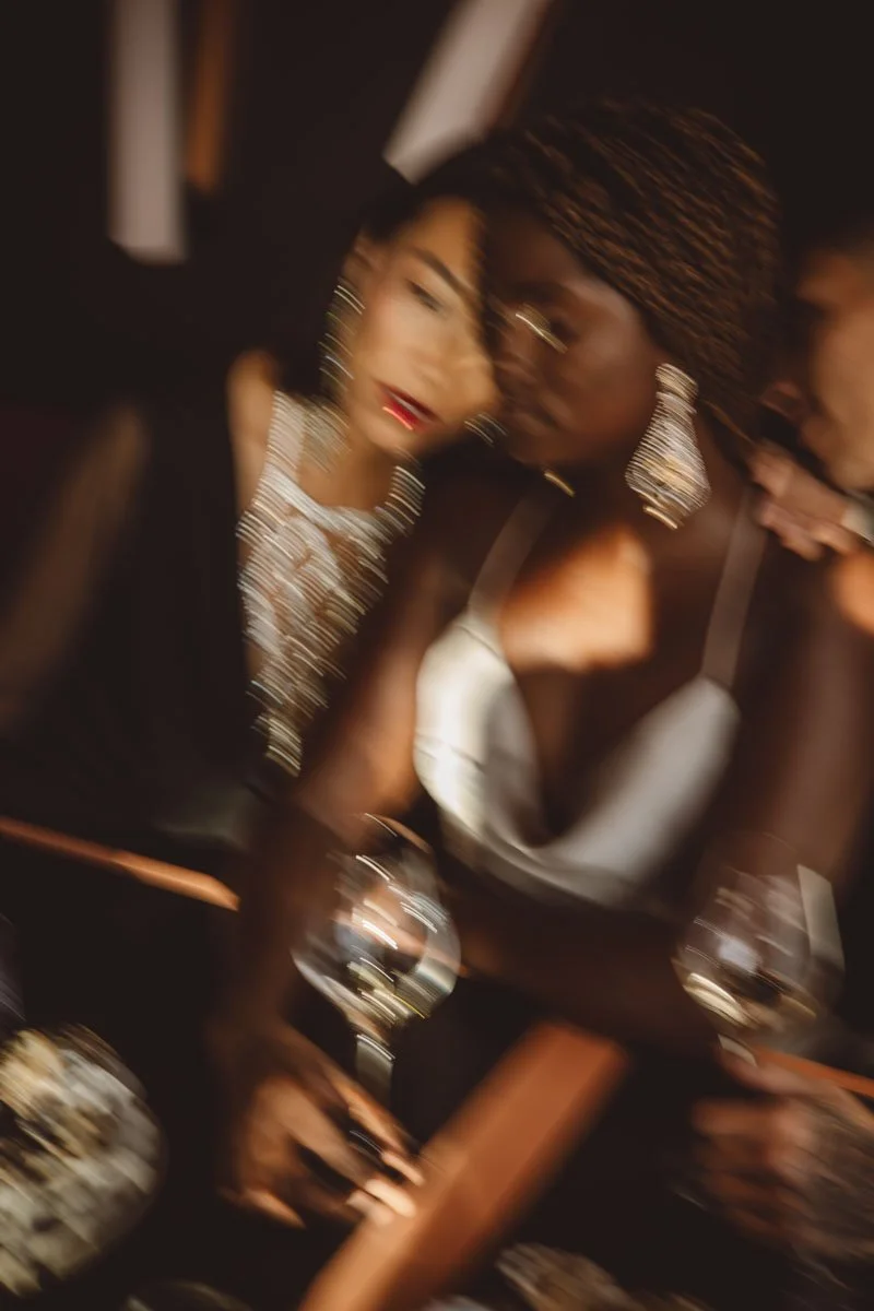 Two women with stylish jewelry and makeup in a social setting, slightly blurred and close together. Restaurant Putaine, Rotterdam, The Netherlands