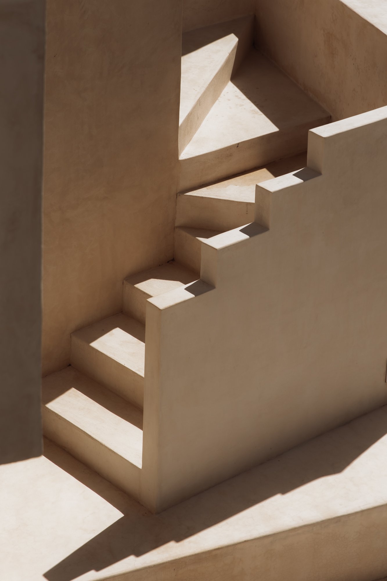 Sunlit staircase with sculptural shadow — modern rustic architecture in Tulu
