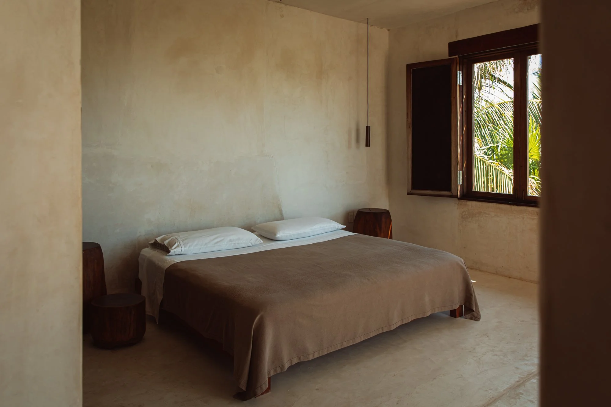 Minimal bedroom with linen bedding and soft afternoon light — Tulum Treehouse interior. Photo by Studio Unfolded