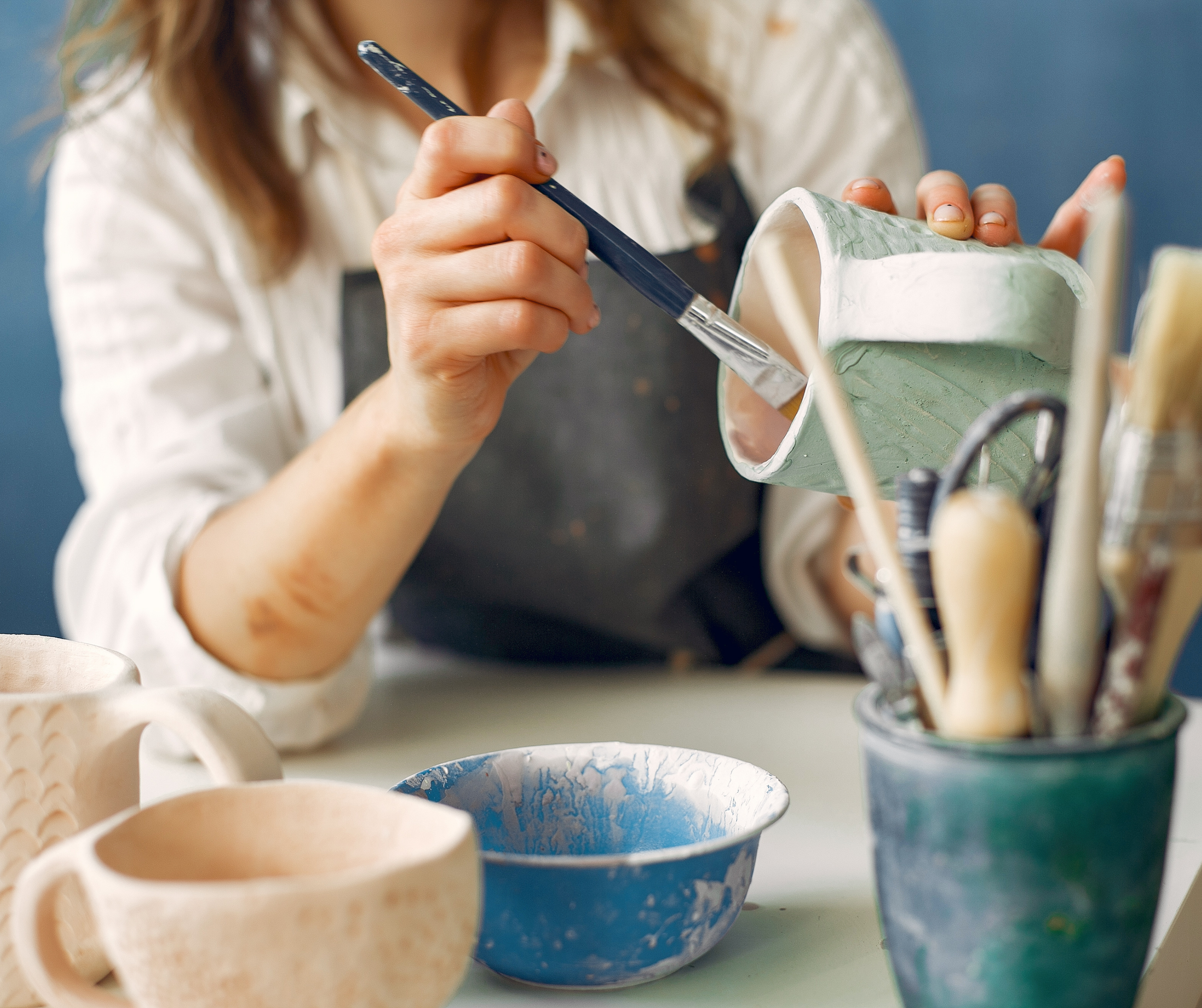 Studio-Norte_womans-hands-painting-pottery-mug-studio.png
