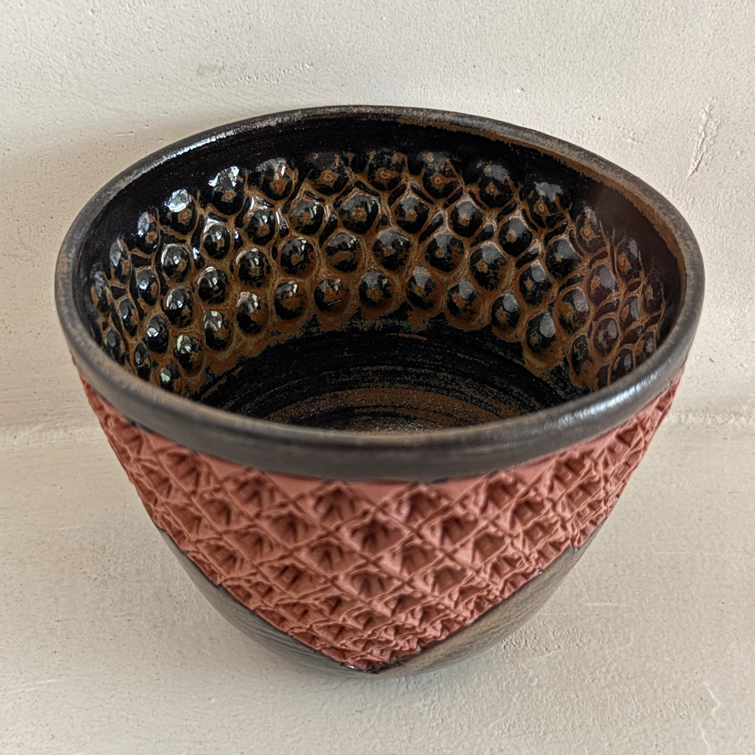 Bol en grès texturé par la technique du repoussé émaillé en partie seulement avec l'émail oeil de tigre laissant apparaître la couleur rouge naturelle de la terre