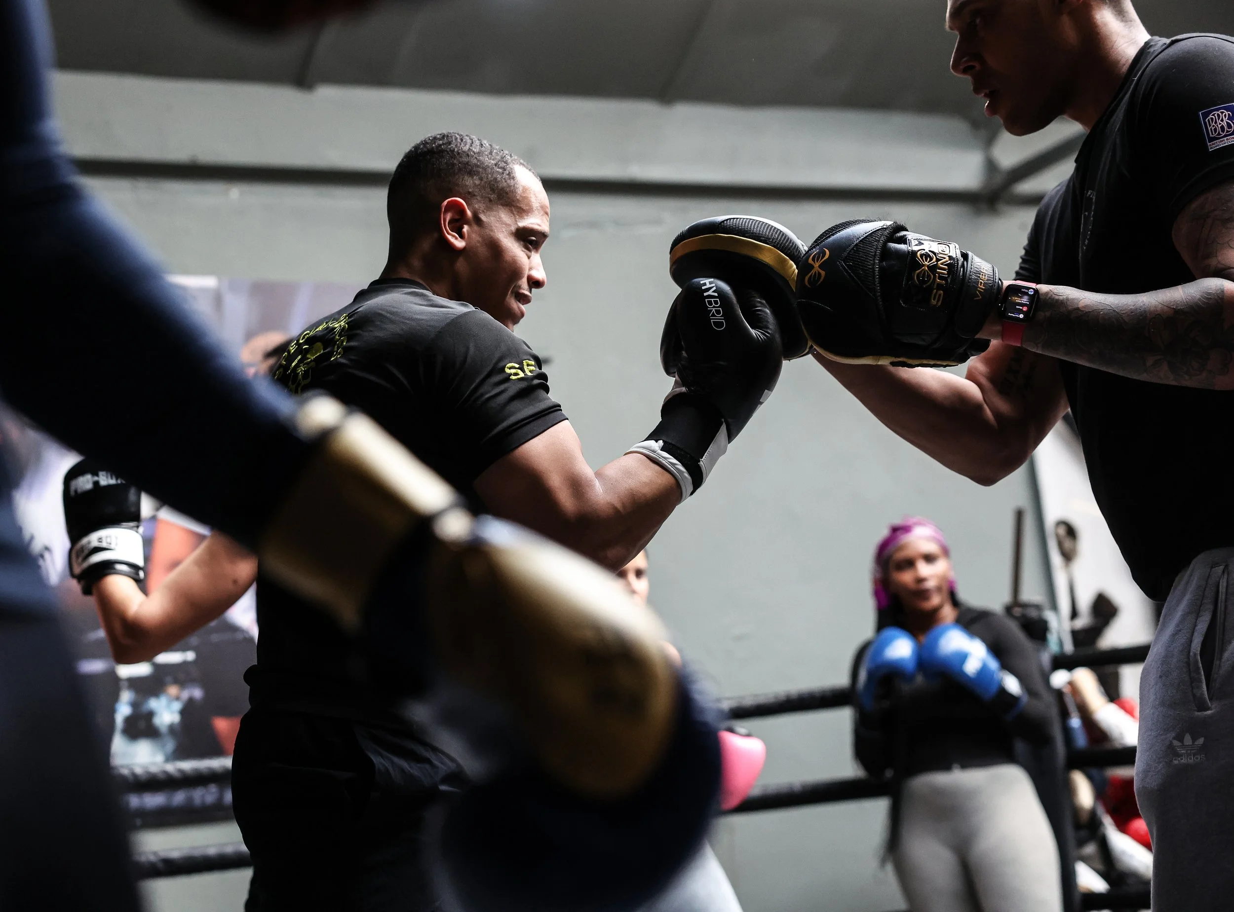 man boxing throwing an uppercut on pads in a group setting in North Finchley