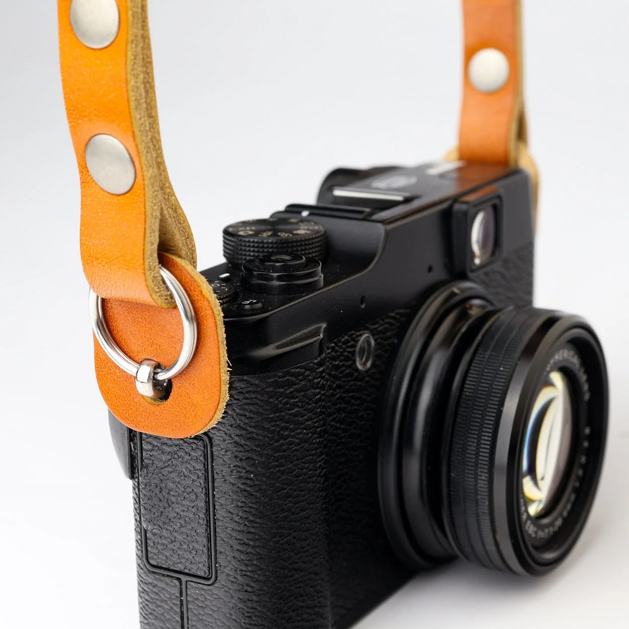Camera strap lug protectors on a Fujifilm camera