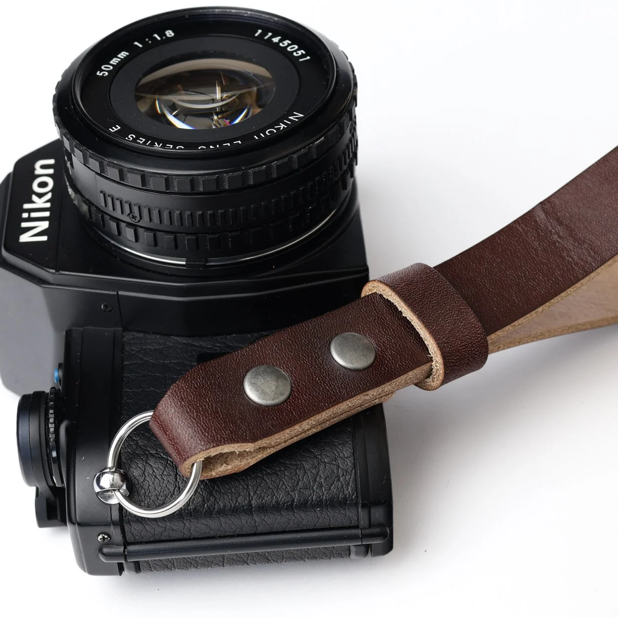Leather wrist strap closeup with black Nikon film camera